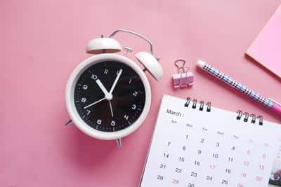 White clock pink background next to a calendar